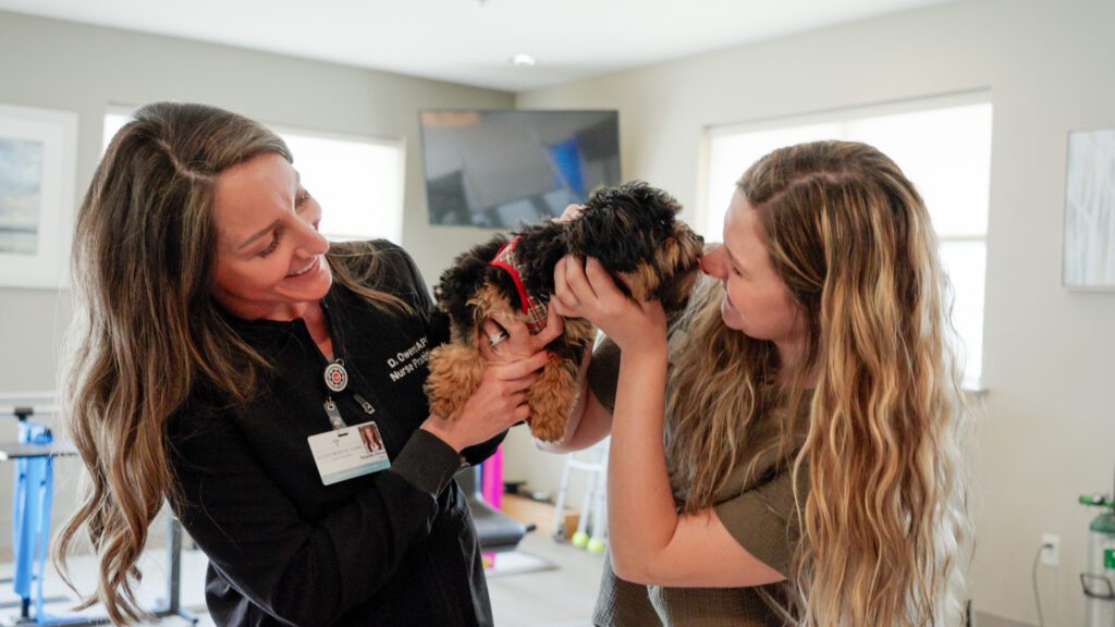 Two nurses hold a dog at a skilled nursing facility