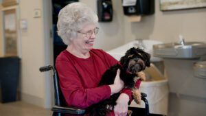 A woman holding a dog at a skilled nursing nursing home