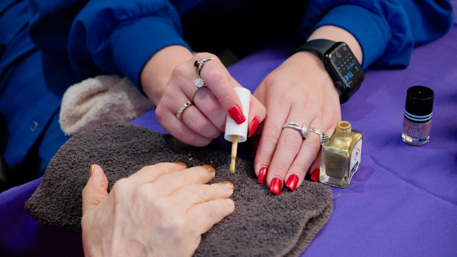 A woman getting her nails painted at a salon at a skilled nursing facility